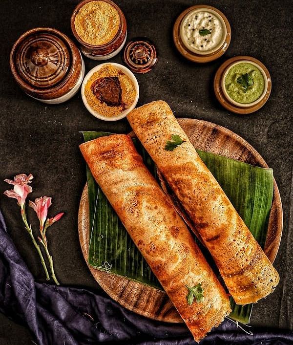 Image of a table with two dosas and a chutneys on the side.